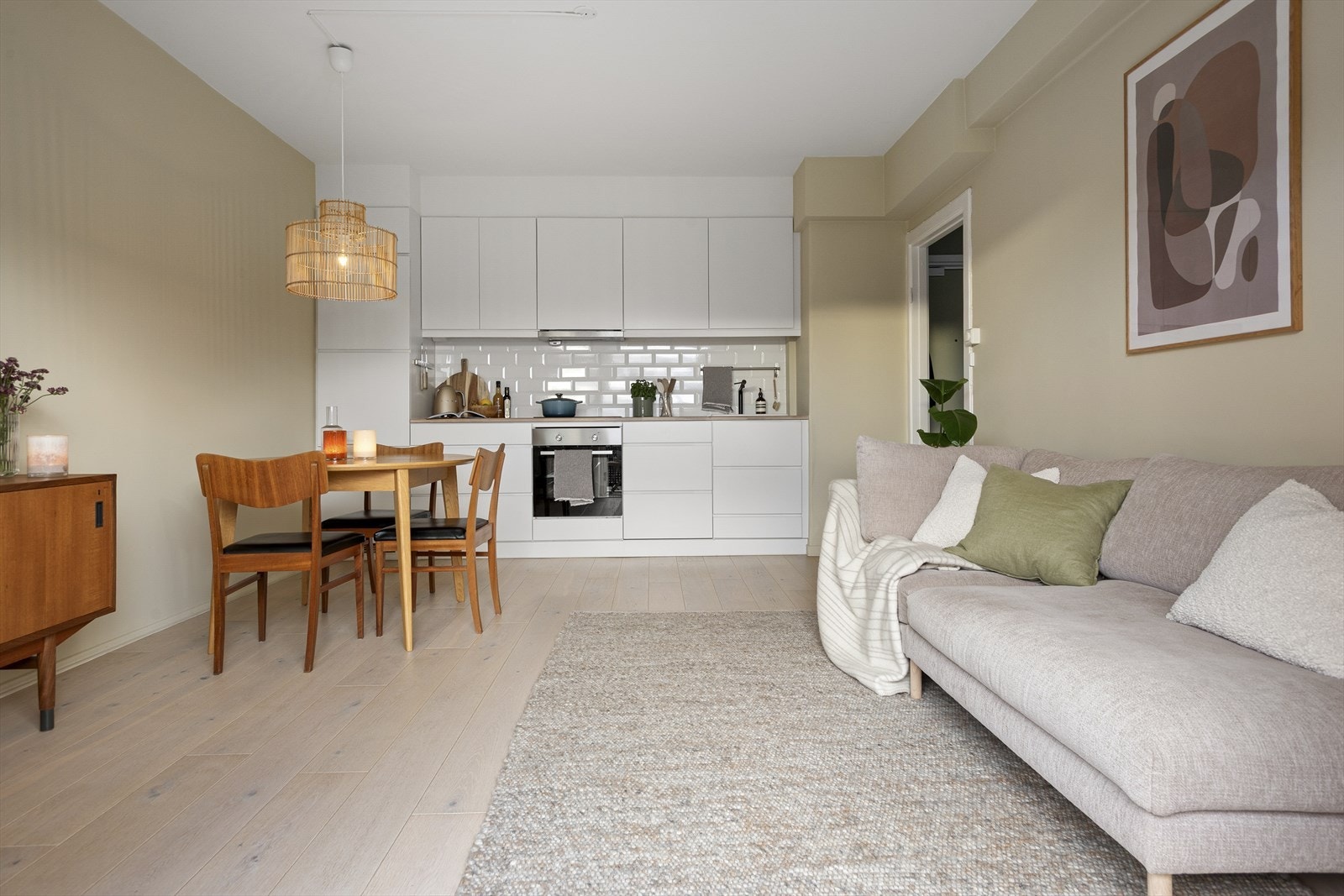 Kvik kjøkkeninnredning fra 2017 med glatte fronter, spotter innfelt i overskap og flis på vegg over benkeplate. Galleribilde