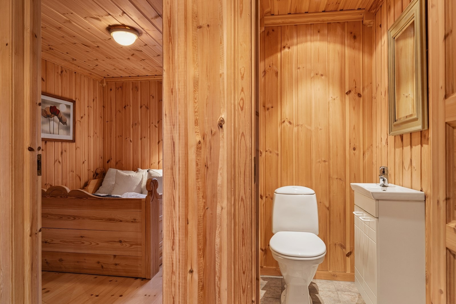 Toalettrommet har fliser på gulvet med elektriske varmekabler, trepanel på vegger og i himling med innfelte spotter. Det er innredet med et gulvmontert toalett og et servantskap med heldekkende servant. Galleribilde
