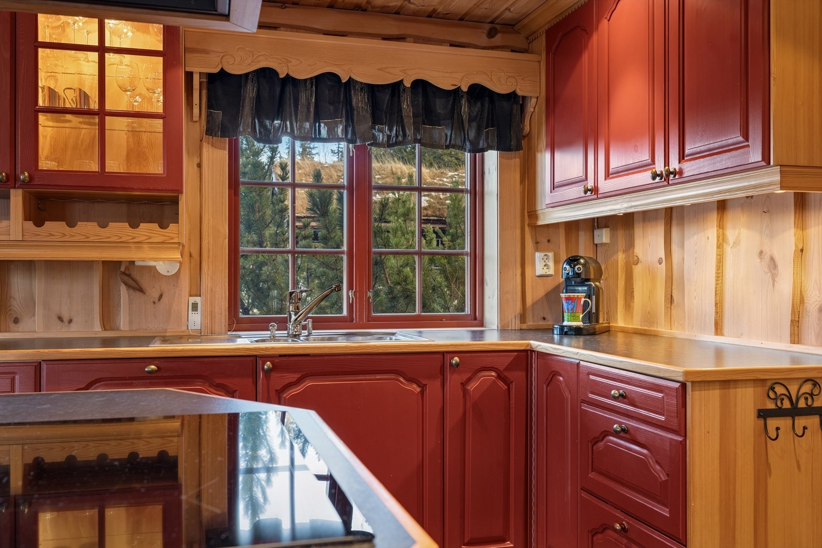 Kjøkkenet fra 2002 har en innredning med profilerte fronter og et overskap med glass, samt laminat benkeplate og nedfelt oppvaskkum i stål. Galleribilde