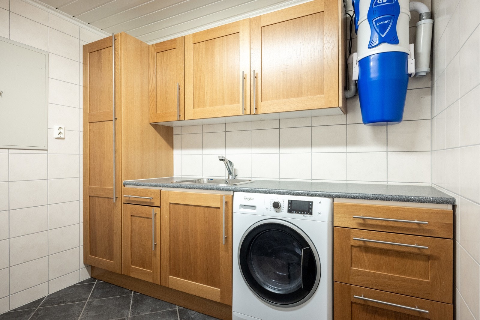 Videre i underetasjen er det et flislagt vaskerom med innredning. Her er det 2 varmtvannstanker og opplegg for vaskemaskin. Galleribilde