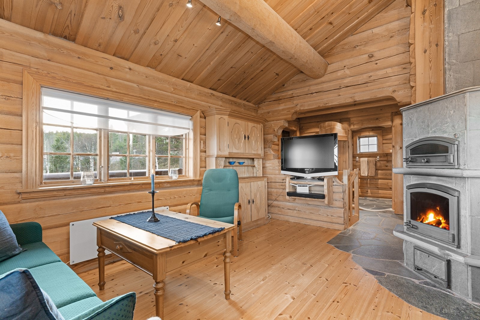 Tregulvet er lagt i sømløs overgang til skiferflisene, og midt i rommet finner man en lekker klebersteinsovn, med egen ''pizzaovn'' i toppen. Galleribilde