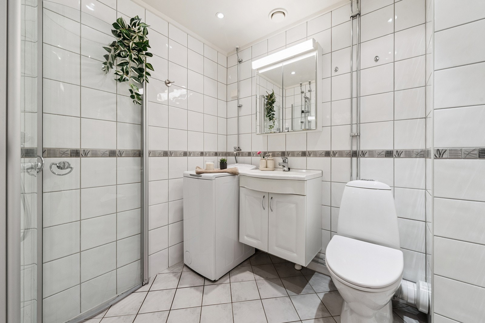 Badet er rehabilitert i regi av brl. i 2006. Godt valg av fliser, varmekabler og downlights. Servant med innredning, toalett, dusj med skyveglass og opplegg for vaskemaskin som følger leiligheten.. Galleribilde