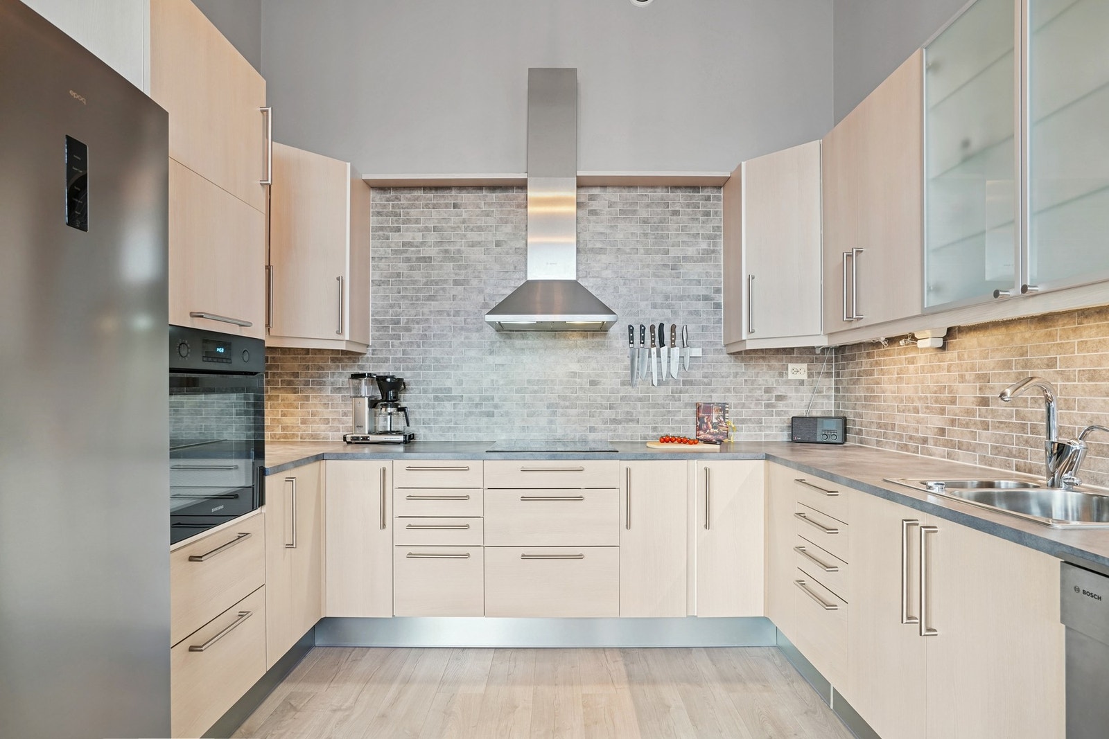 Flott og innholdsrikt kjøkken fra HTH med glatte fronter og fliser på vegg over laminat benkeplate. Galleribilde