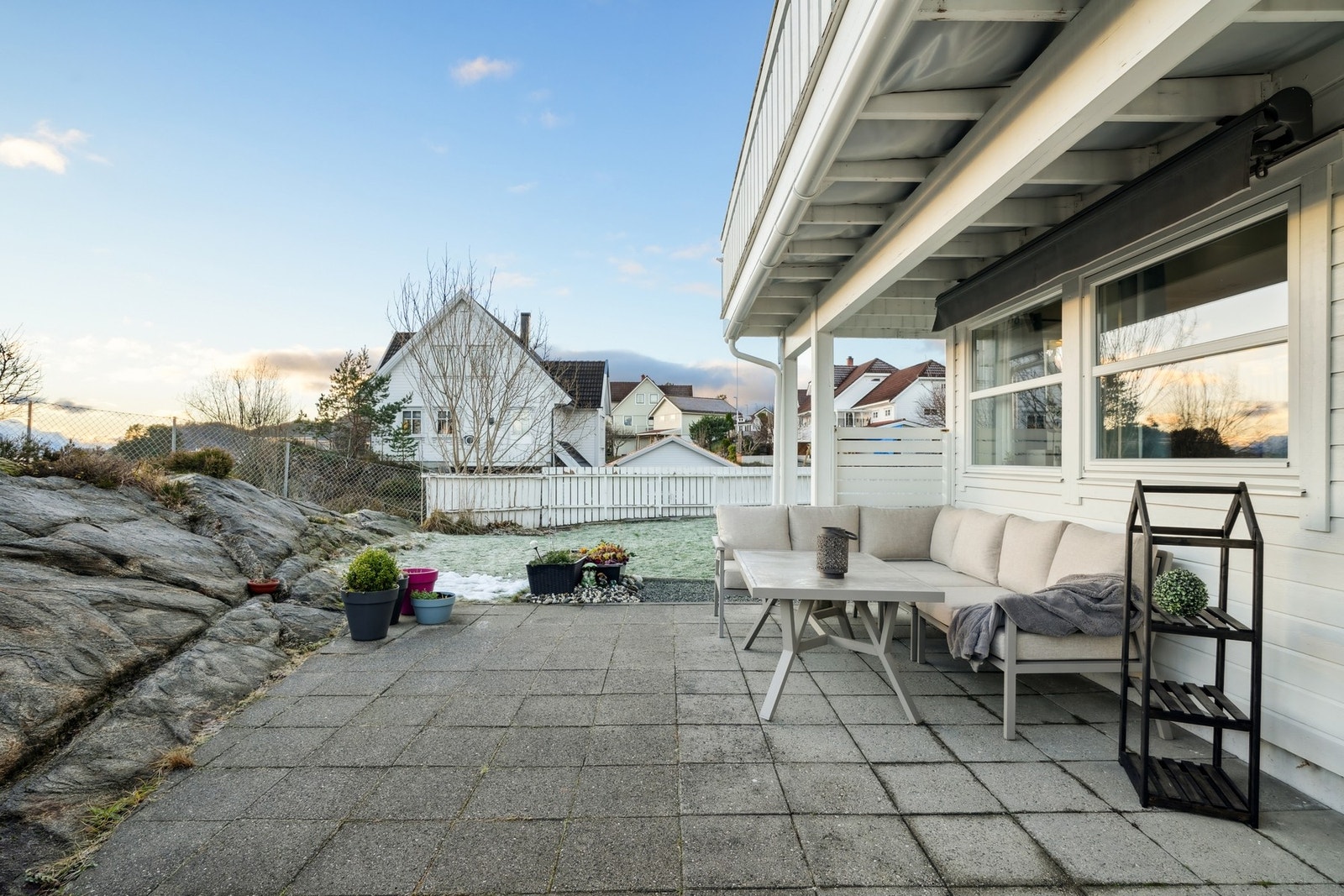 Skjermet uteplass på bakkeplan med heller og markise på vegg. Galleribilde