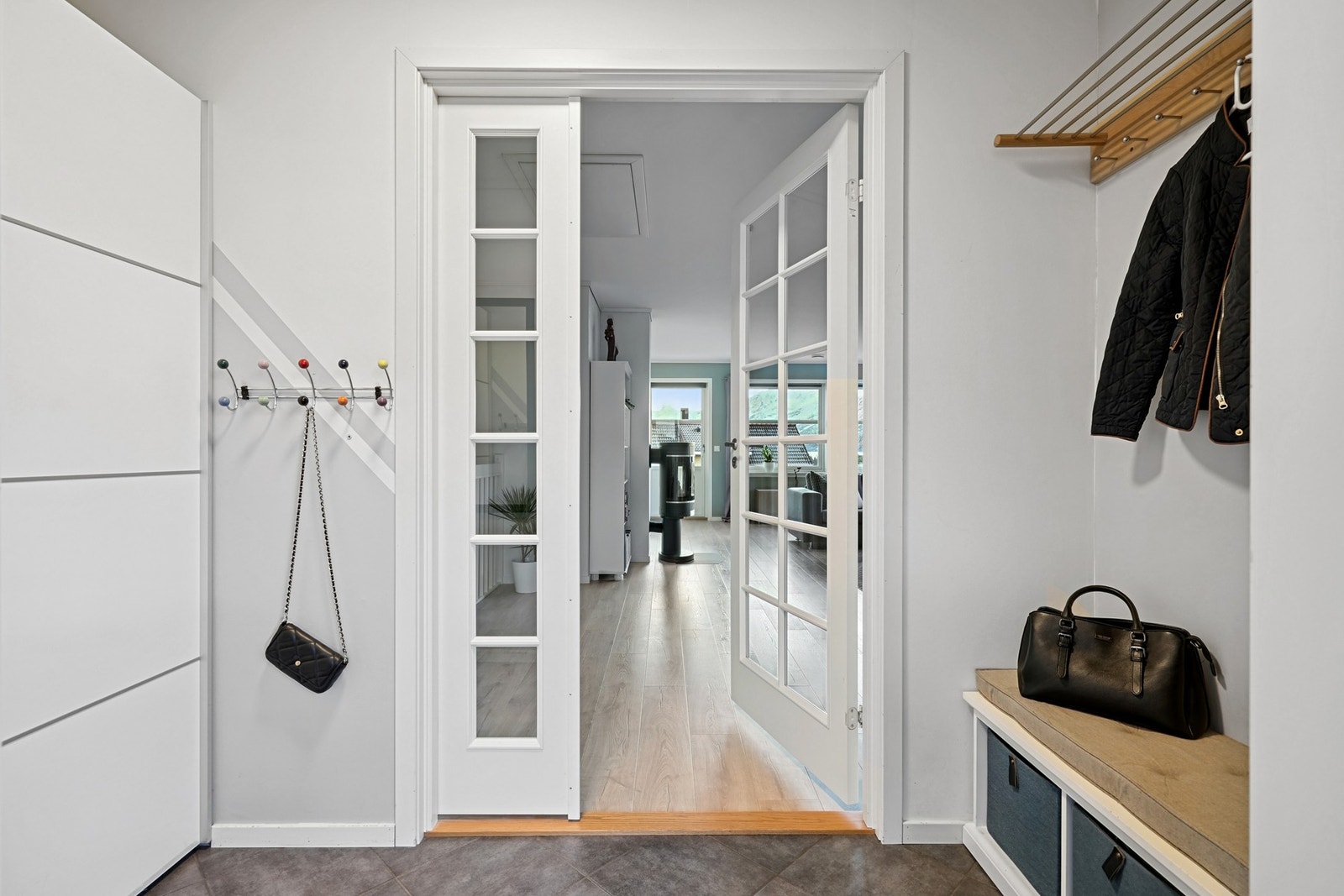 Lyst og trivelig vindfang med flislagt gulv og garderobeskap med skyvedører. Lampen i gangen har 3 lysstyrker. Galleribilde