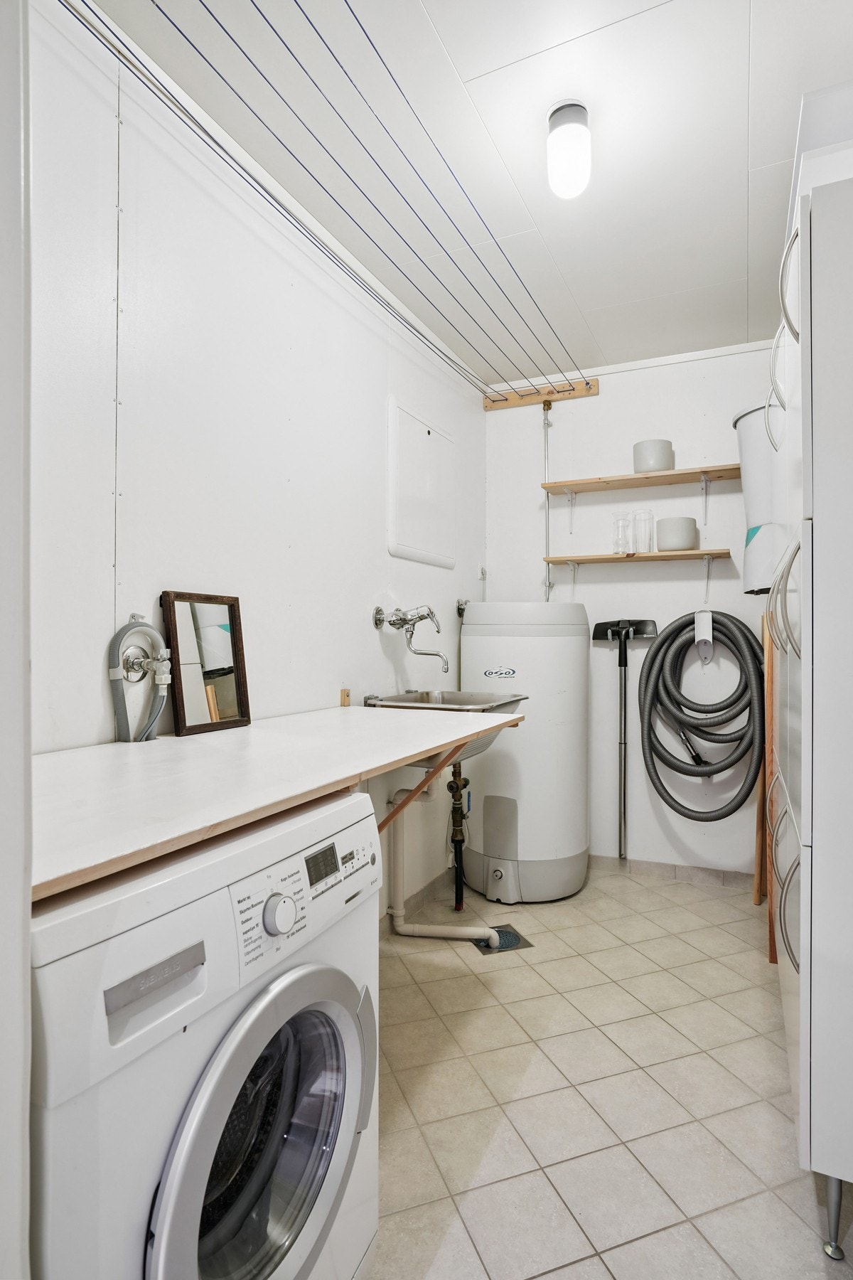 Praktisk vaskerom med benkeplate, utslagsvask og opplegg for vaskemaskin. Galleribilde