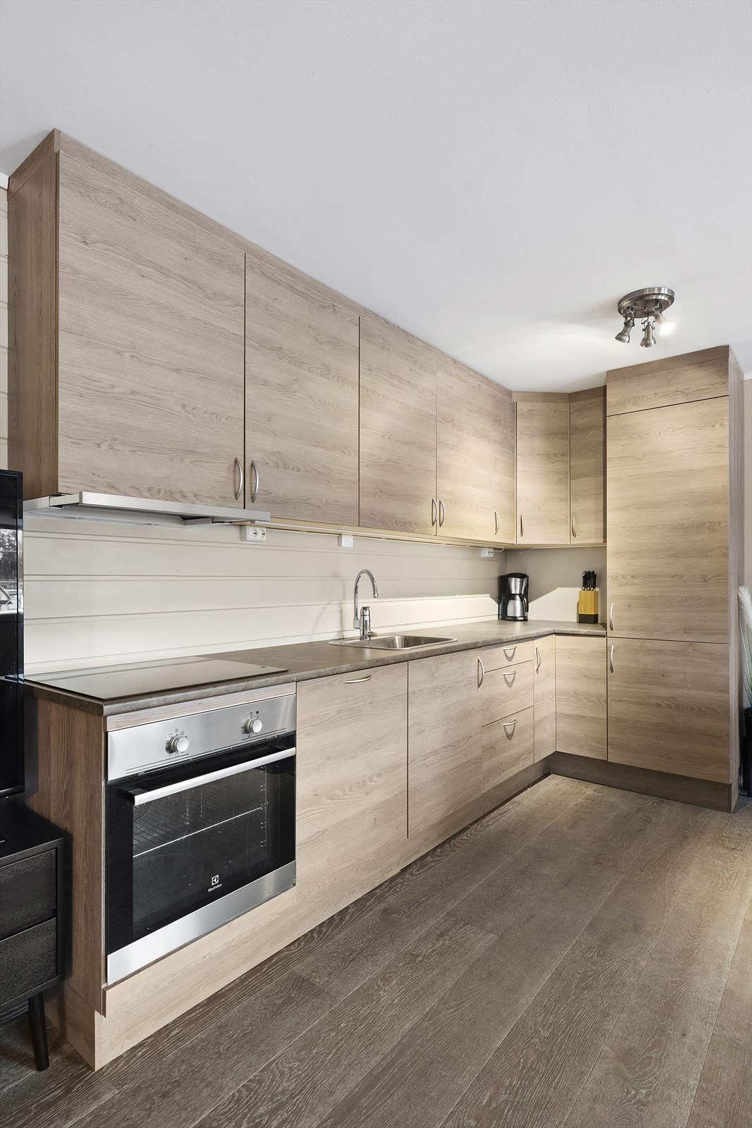 Innbydende kjøkken med slette fronter og laminert benkeplate. Kjøkkenet tilbyr godt med oppbevaringsplass i takhøy innredning Galleribilde