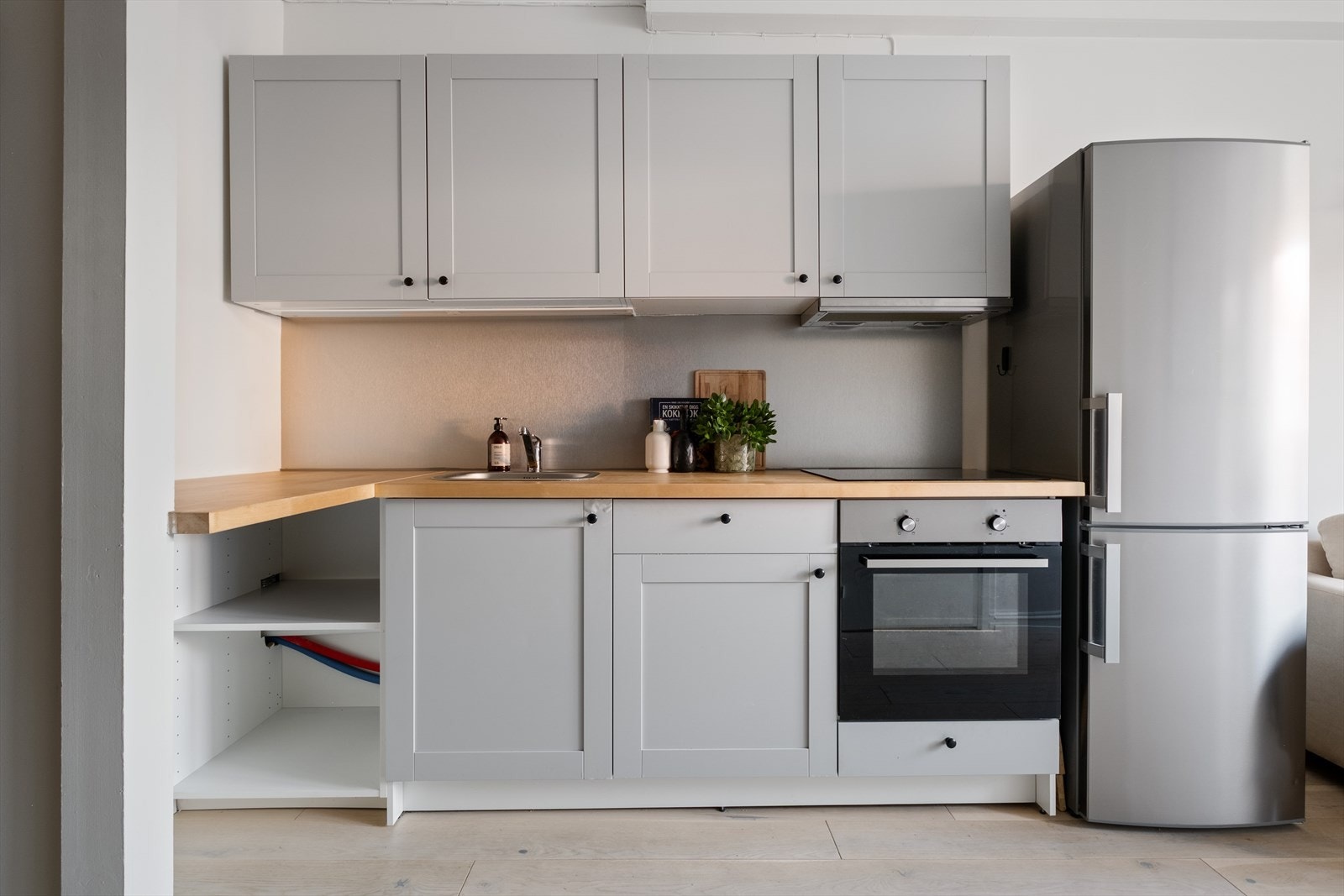 Kjøkkenet har innredning med profilerte fronter og benkeplaten er av heltre. Av integrerte hvitevarer er det komfyr og platetopp. Frittstående kjøl/frys. Plate mellom over- og underskap. Galleribilde