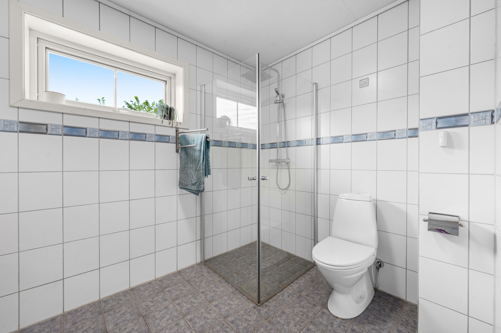 Flislagt bad med dusj, servant og toalett. Galleribilde