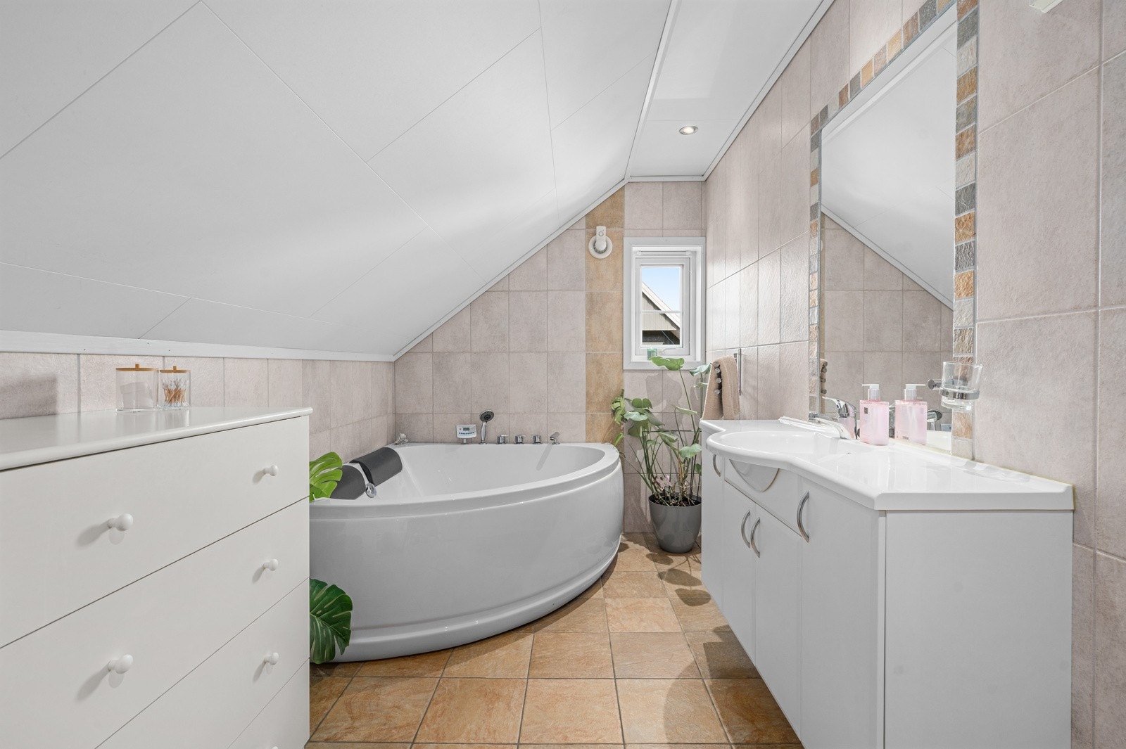 Flislagt bad fra byggeår med badekar, servant og vegghengt toalett. Gulvet har fliser på betong og det er varmekabler. Galleribilde