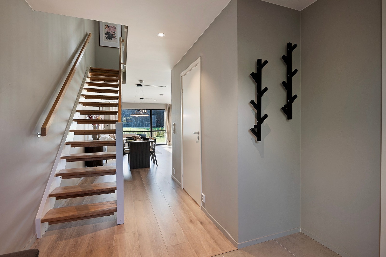 De store vindusflatene i enden av stuen gjør at blikket naturlig trekkes videre innover i boligen og forsterker den åpne, luftige romfølelsen Galleribilde