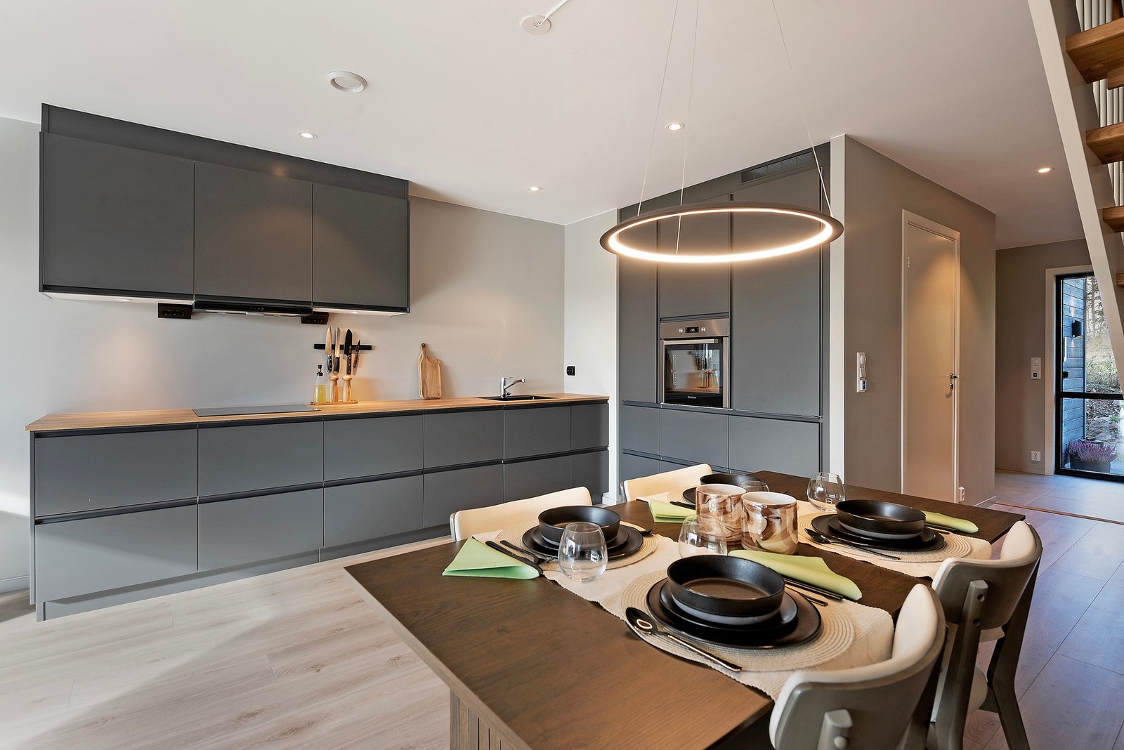 Den matte, mørke kjøkkeninnredningen skaper et tydelig skille og definerer kjøkkenområdet samtidig som den gir et moderne og elegant uttrykk Galleribilde