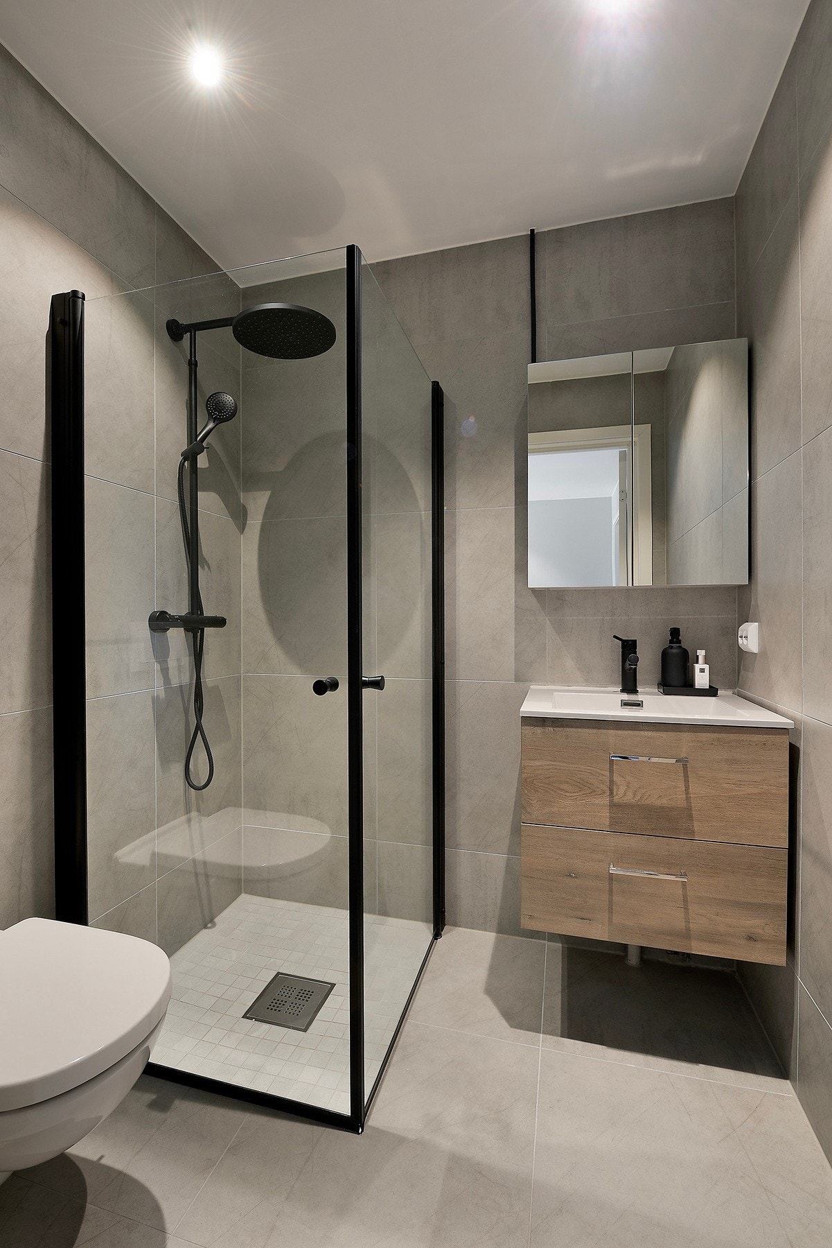 Begge badene i boligen er elegant flislagt med varmekabler i gulvet, og innredet med speilskap, dusjhjørne, vegghengt toalett og servantinnredning med skuffer Galleribilde