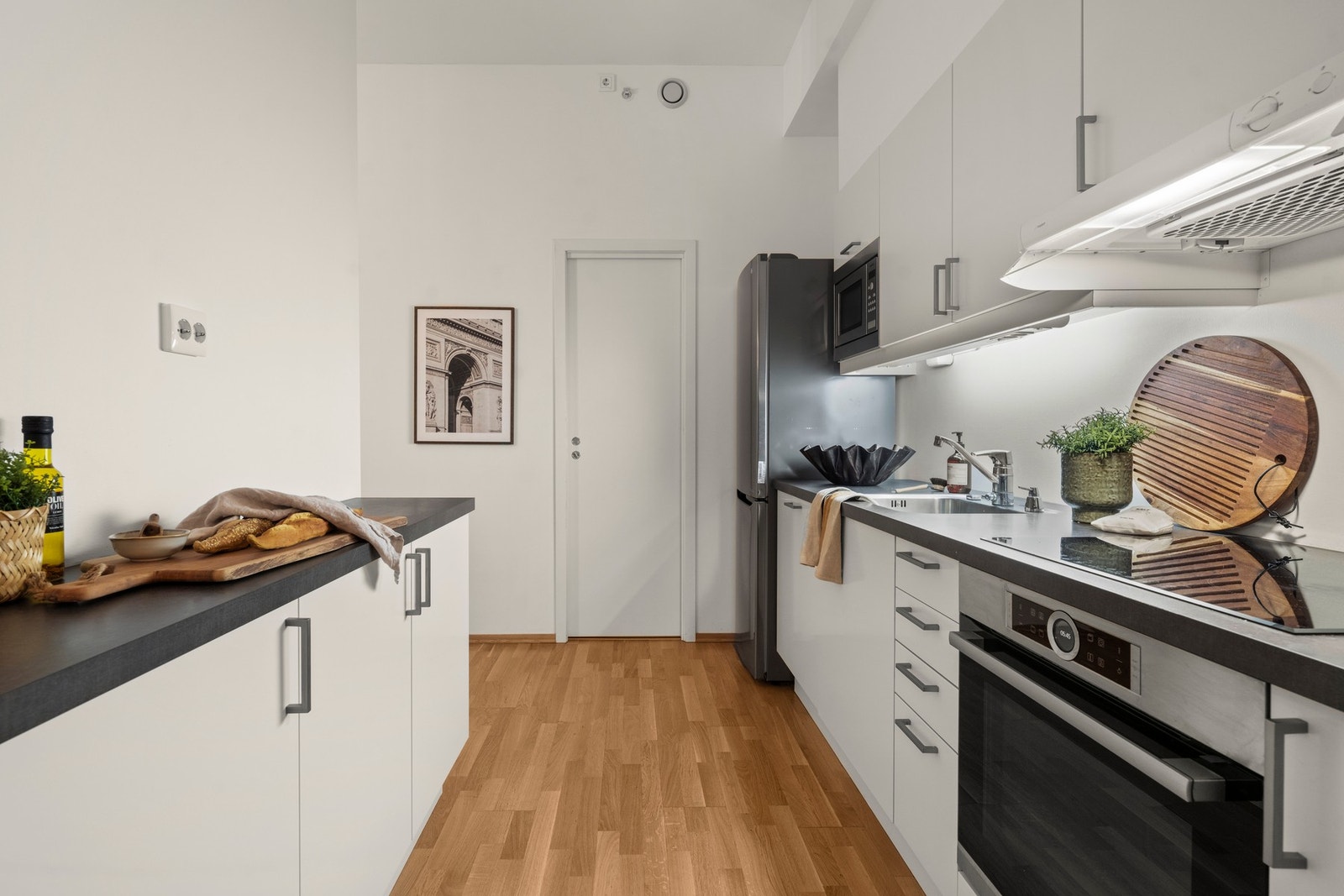 Kjøkkenet har glatte, hvite fronter, laminat benkeplate og nedfelt oppvaskkum. Galleribilde