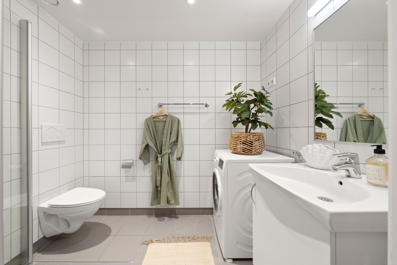 Moderne bad med lyse fliser, elektrisk gulvvarme og stilren innredning. Galleribilde