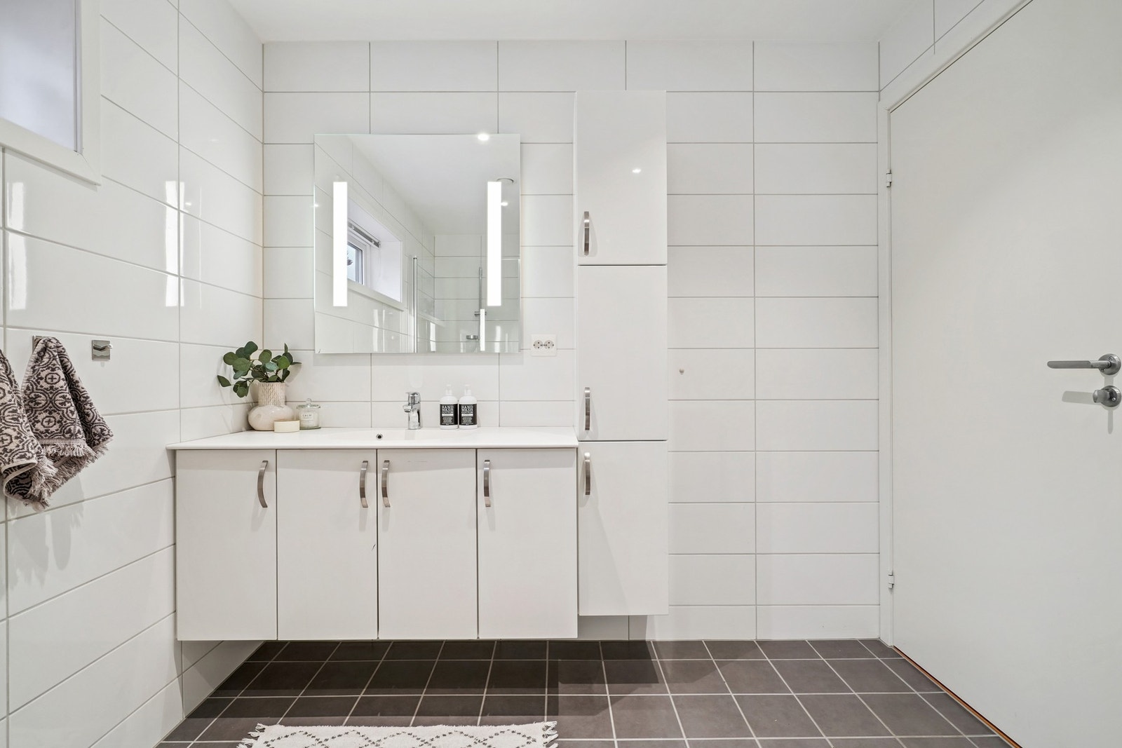 - servantinnredning med hvite høyglans fronter, helstøpt kompositt servantplate, speil med integrert belysning og et høyskap. Opplegg for vaskemaskin. Galleribilde