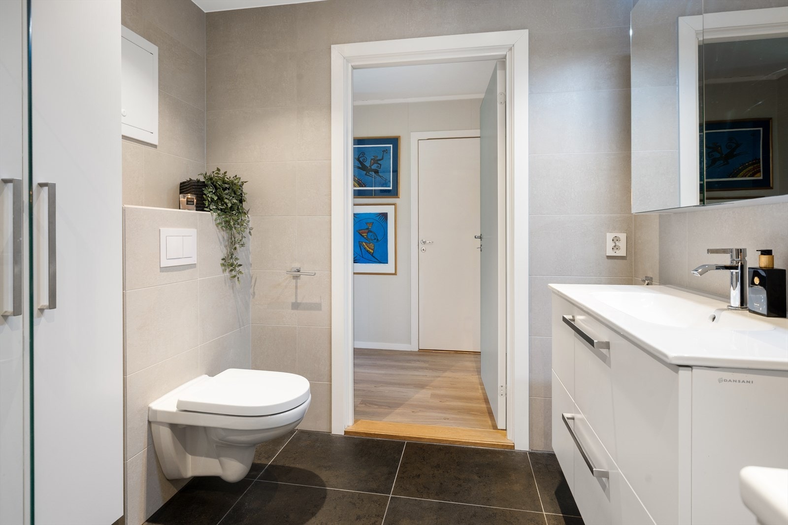 Badet er innredet med med servant, speilskap med belysning, veggmontert toalett, dusjvegg i herdet glass og opplegg for vaskemaskin. Galleribilde