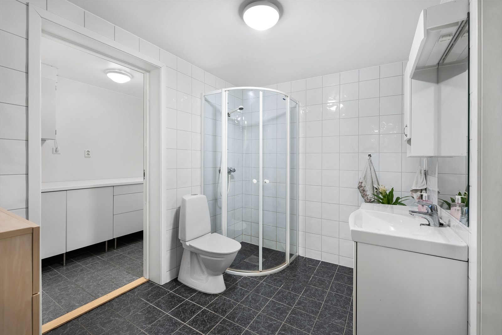 Romslig og moderne baderom. Helfliset og lettholdt. Inngang til et meget praktisk vaskerom. Galleribilde