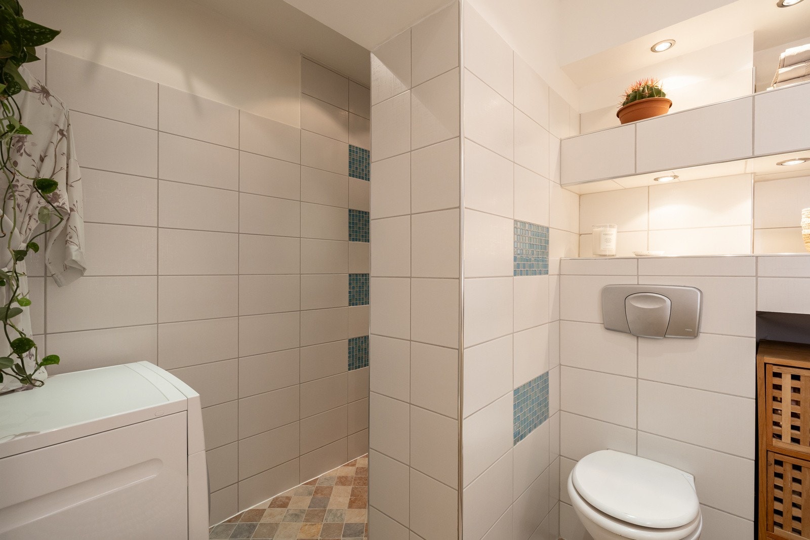 Baderommet inneholder servant med underskap (2023), speil med lys over servant, toalett og opplegg for vaskemaskin. Galleribilde