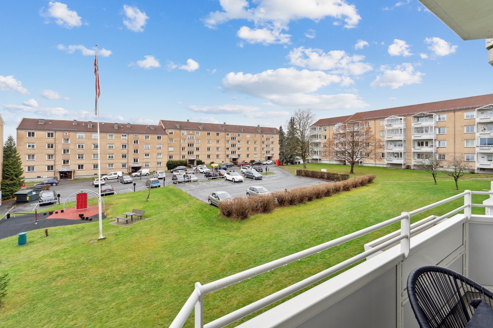 Utsikt fra balkongen til borettslagets velstelte og fine grøntområder med lekeplass. Galleribilde