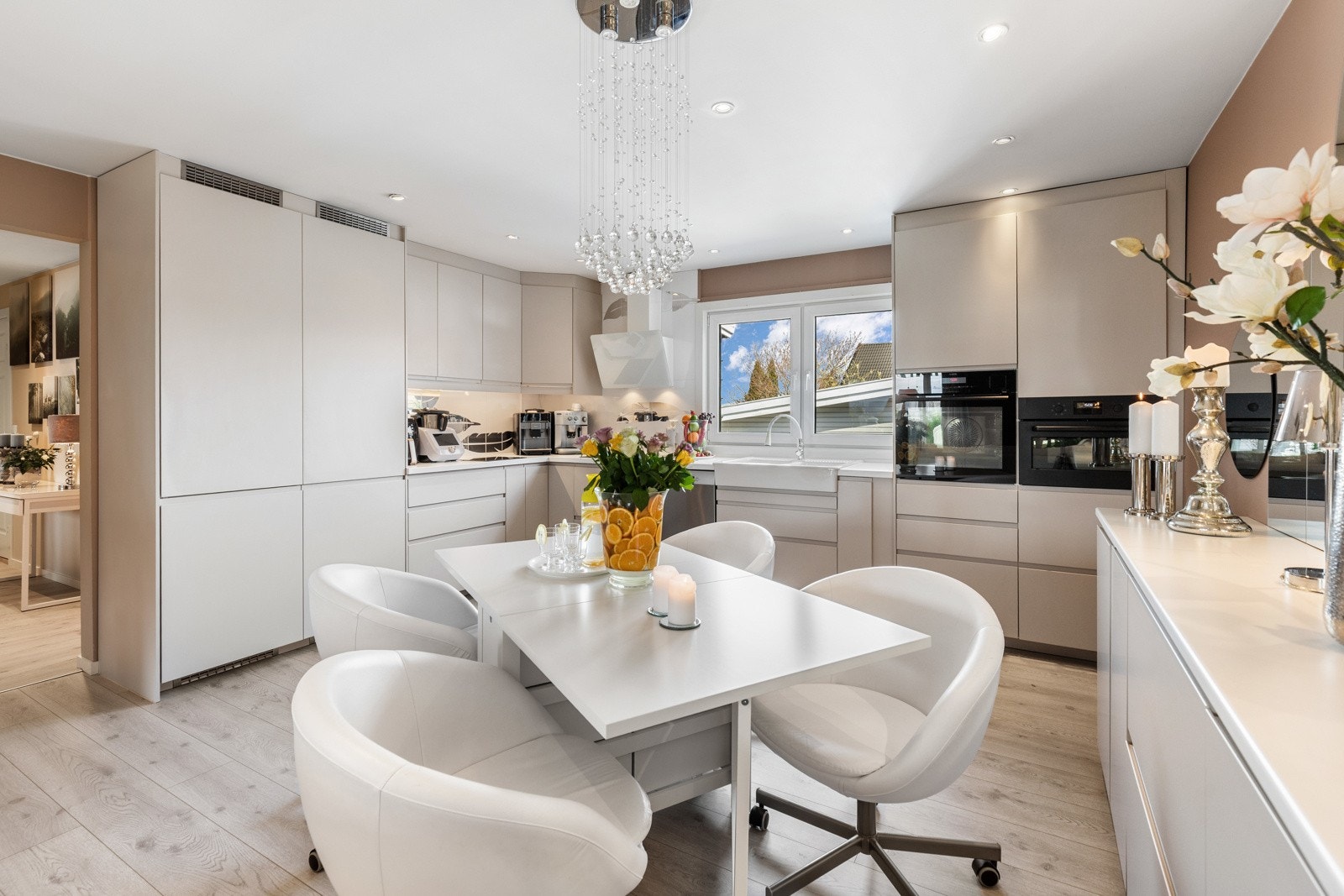 Innredningen fra Ikea har hvite, glatte fronter, takhøye skap og hvit laminatbenkeplate med hvit oppvaskkum i porselen. Galleribilde