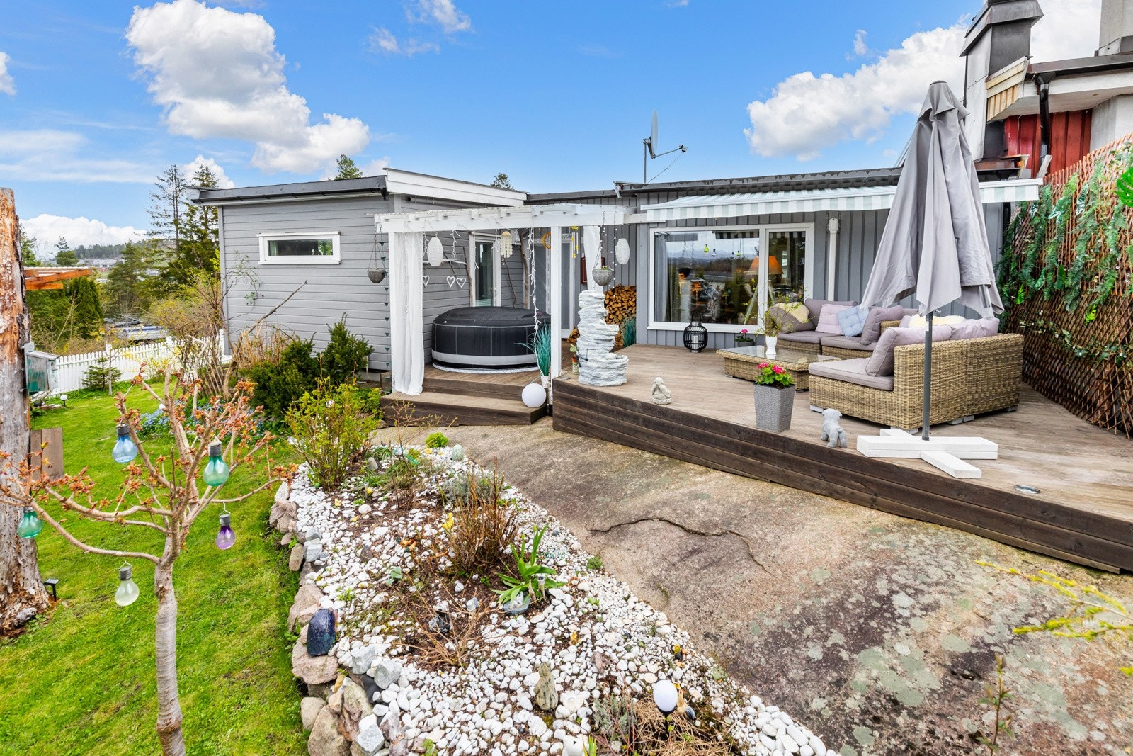 Tomten er pent opparbeidet med gressplen, frodige bed og noe fjell i dagen, samt gruslagt gårdsplass og vintergrønne prydbusker. Galleribilde