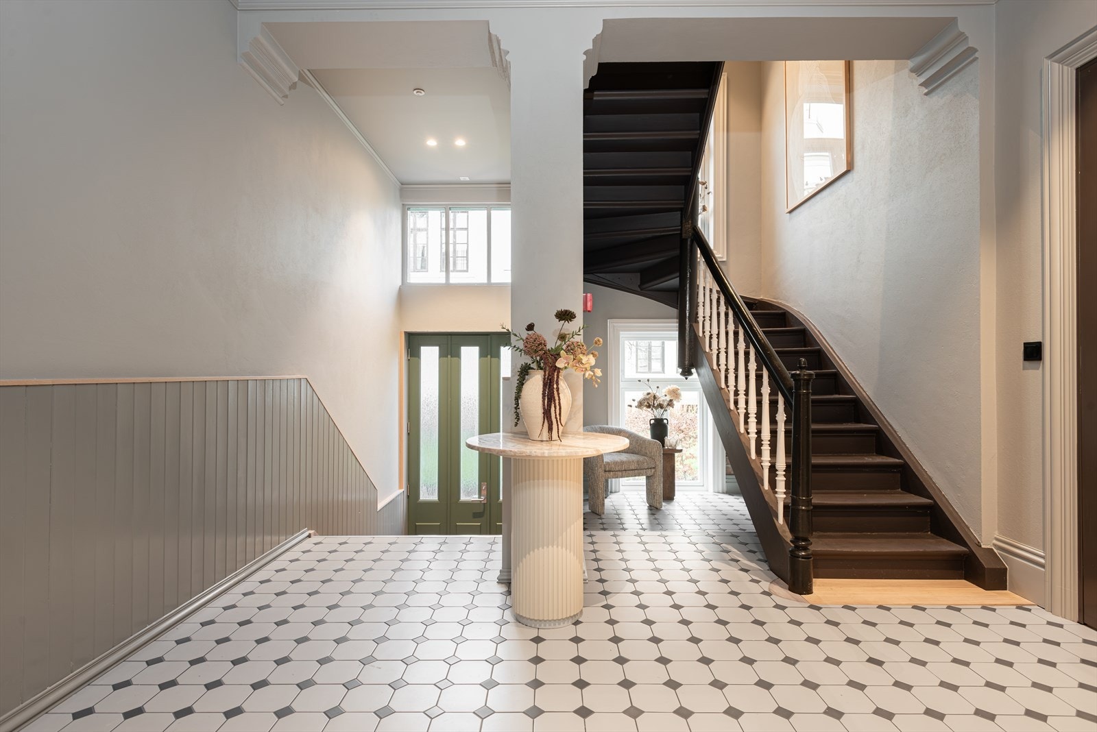 Lekre fliser og brystning i faspanel med eikelist - Den originale trappen er bevart og malt, og den synlige patinaen gir en vakker kontrast til de nye materialene og de lyse fargene Galleribilde