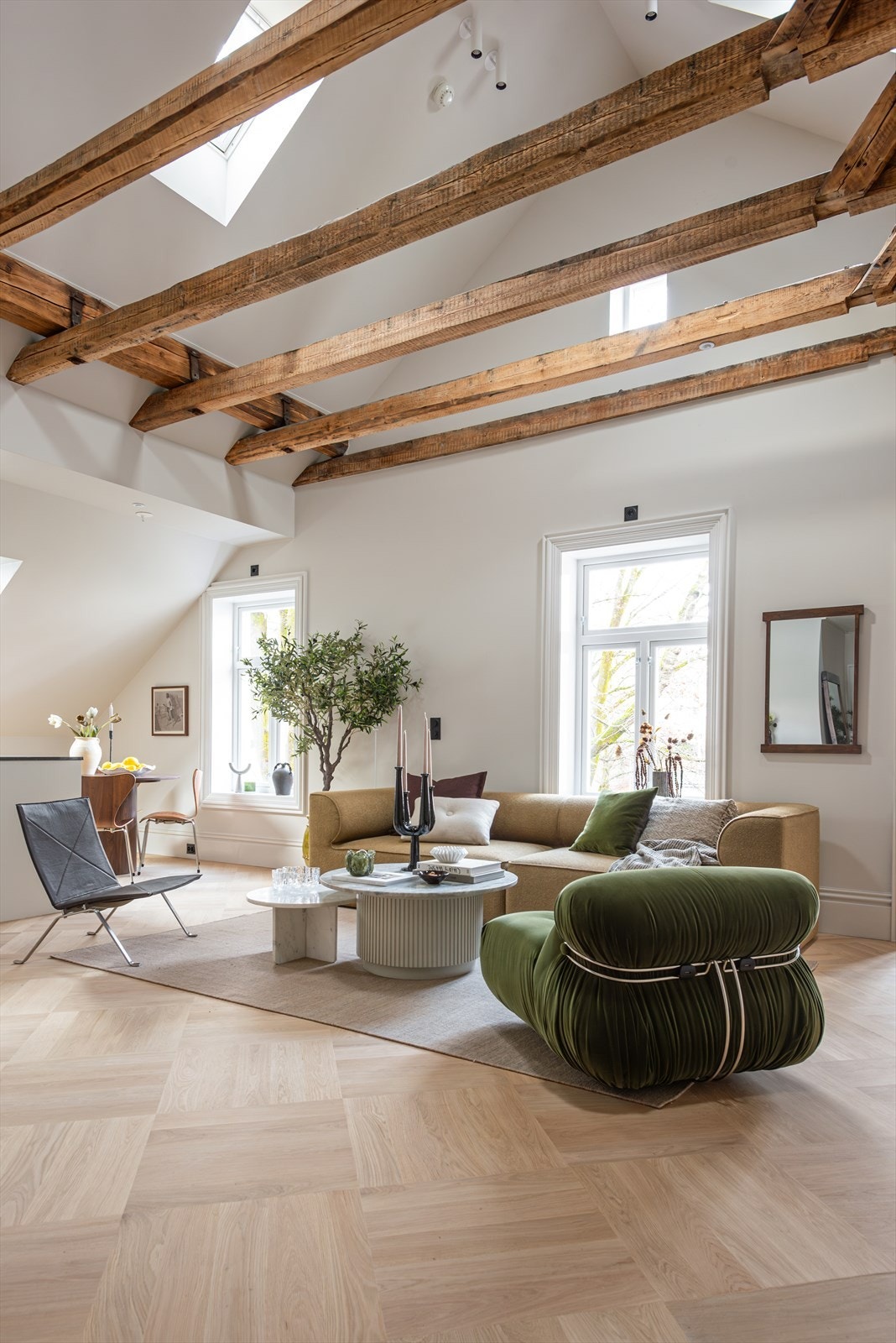 Store vindusflater gir rikelig dagslys, og i kombinasjon med den høye himlingen får stuen en åpen og luftig atmosfære Galleribilde