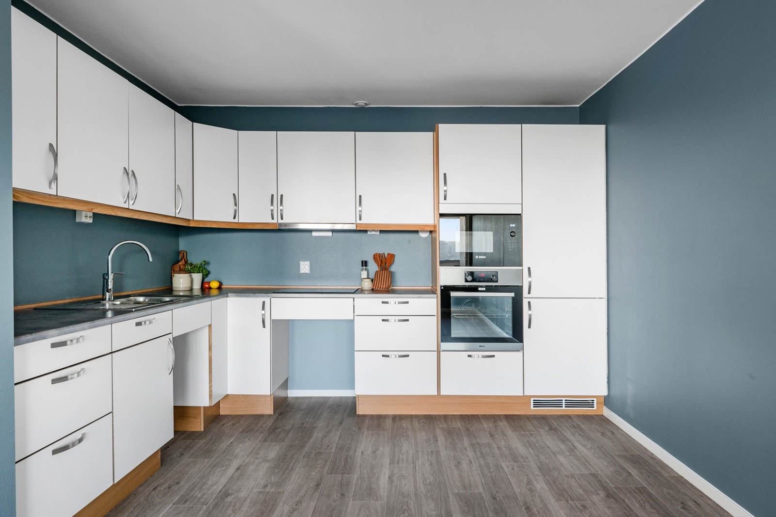 Pent kjøkken med kjøkkeninnredning fra Sigdal kjøkken fra 2020. Det er innfelte hvitevarer som koketopp, stekeovn, mikro og kjøl/fryseskap. Galleribilde