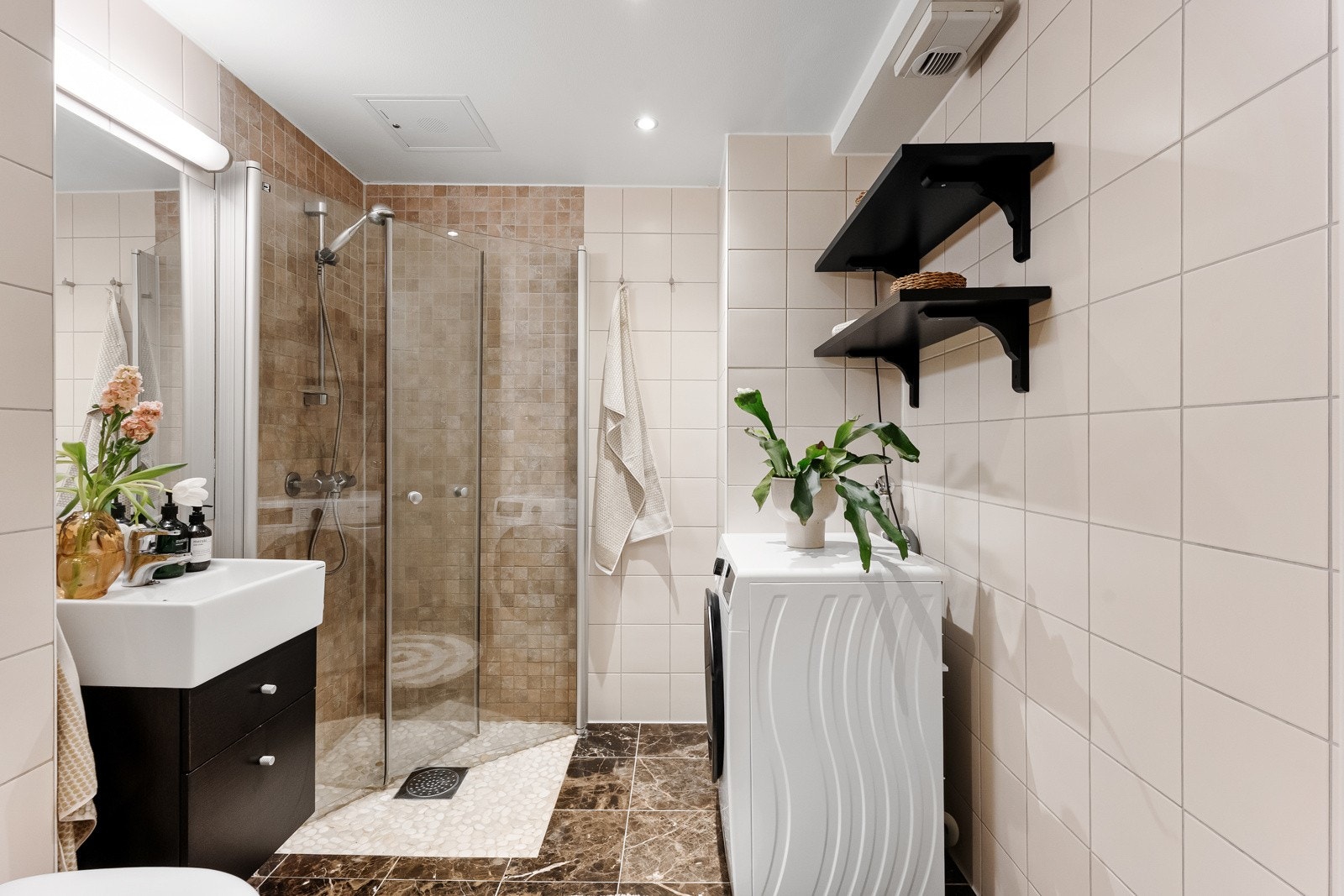 Flislagt baderom, også fra 2010, utført i lyse fliser med downlights i himling. Opplegg for vaskemaskin Galleribilde