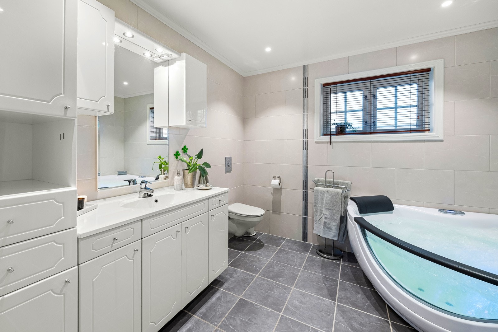 Stort flislagt hovedbad, fra byggeår. Badet har flislagte gulv- og veggflater, samt varmekabler i gulvet for ekstra komfort. Innredningen består av klassisk servantmøblement med over- og underskap, tilhørende høyskap, samt speil. Galleribilde