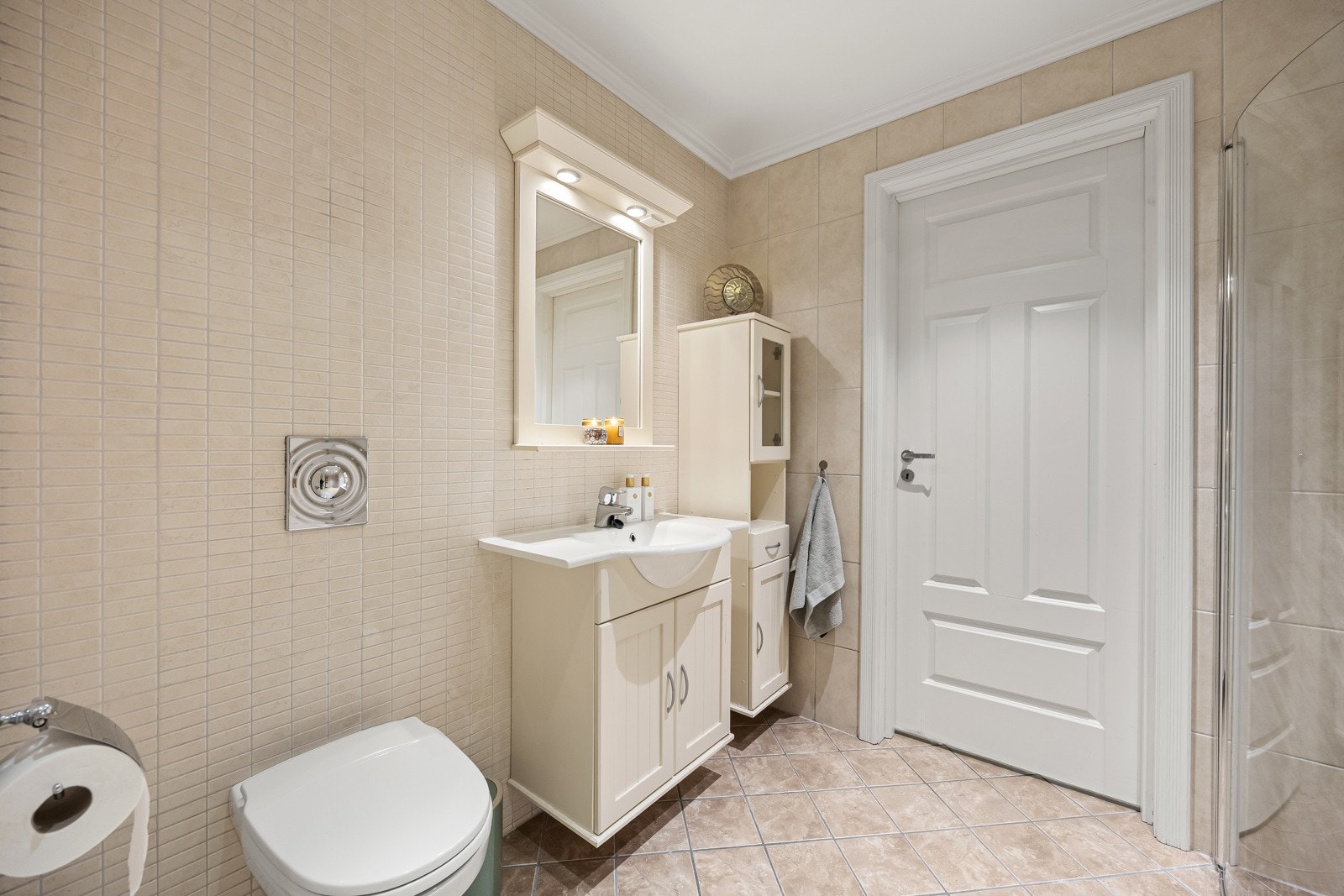 Flislagt bad nr. 2 i boligens 1. etasje, fra byggeår. Badet har flislagte gulv- og veggflater, samt varmekabler i gulv. Innredningen består av klassisk servantmøblement med underskap, speil, samt to tilhørende høyskap. Galleribilde