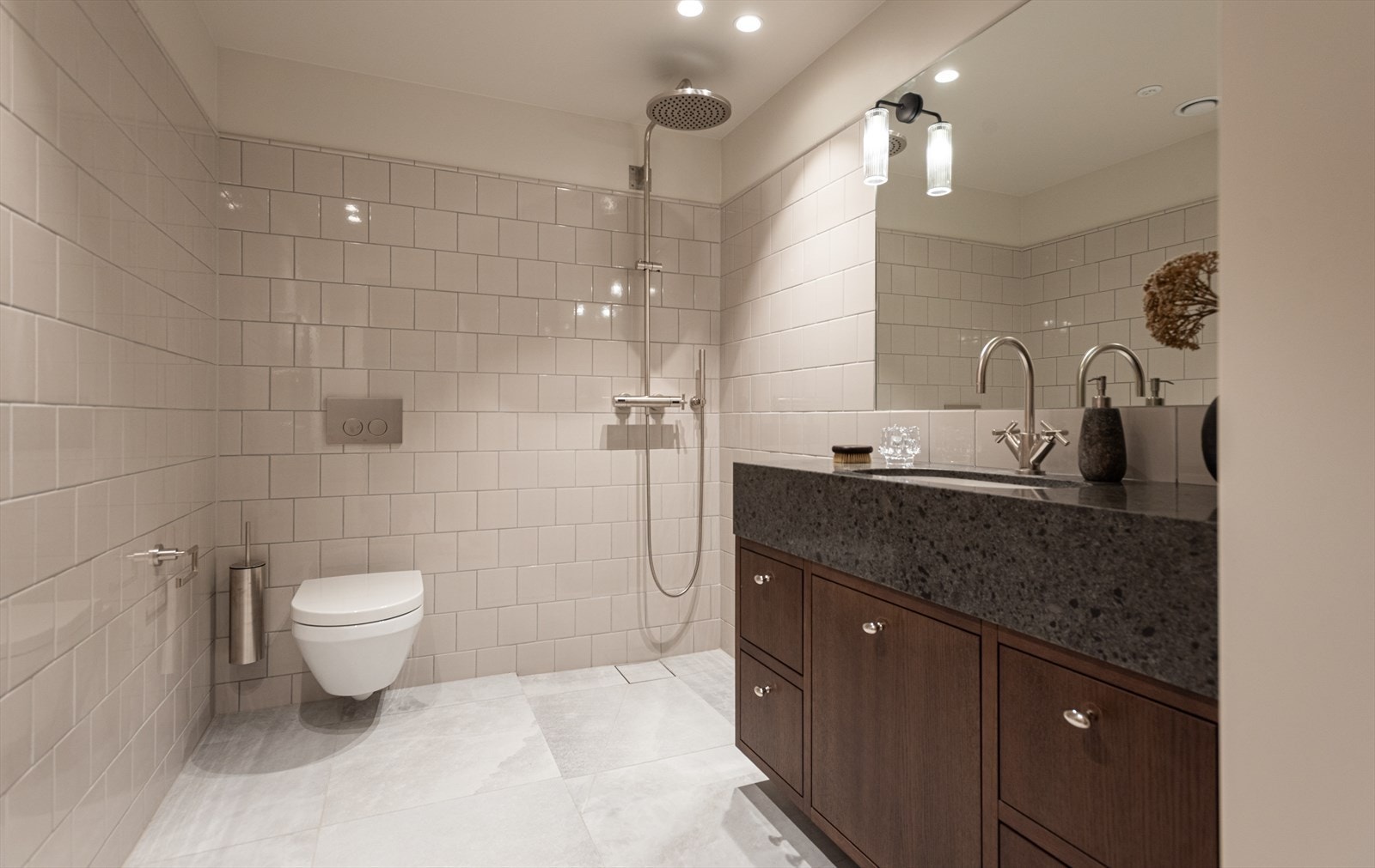 Badene har elektriske varmekabler og vannbåren varme, veggfestet wc, belysning fra Corston, armaturer og garnityr fra Dornbracht samt skjult varmevegg for håndklestenger Galleribilde