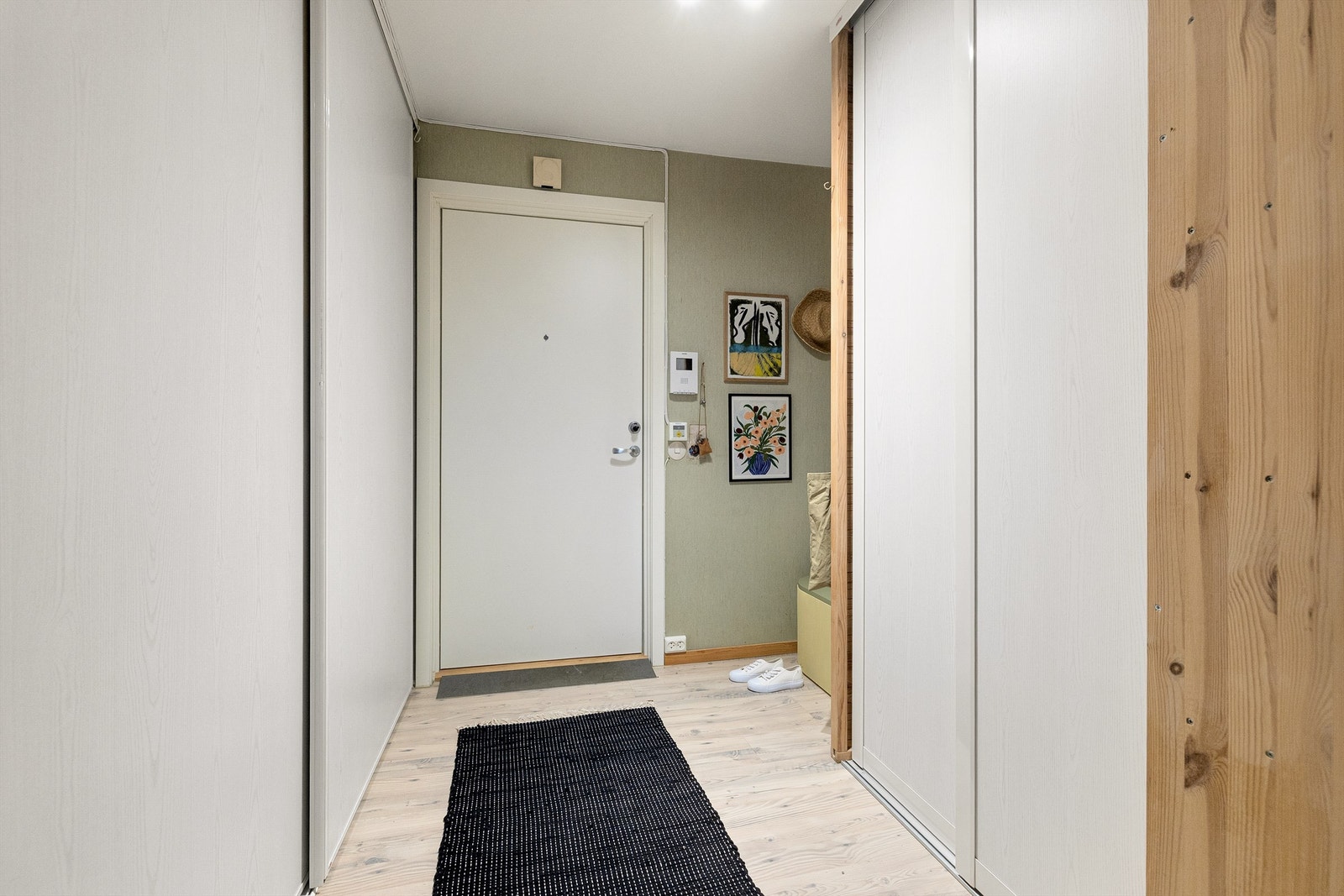 Romslig og innbydende entré med laminat på gulv. De lyse overflatene gir et luftig førsteinntrykk, samtidig som den praktiske løsningen gir rikelig med plass til klær og sko. Galleribilde