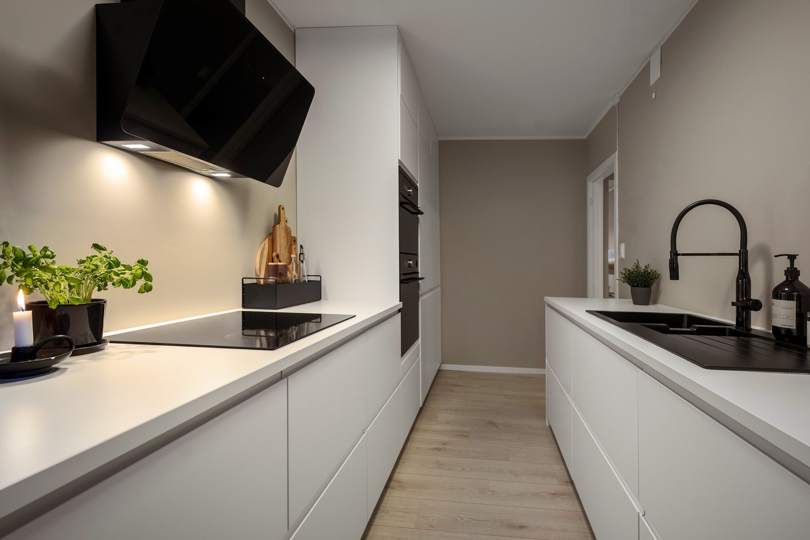 Kjøkkenet er innredet med integrerte hvitevarer som oppvaskmaskin, platetopp med vifte over, stekeovn og kombiovn, et fryseskap og et kjøleskap Galleribilde