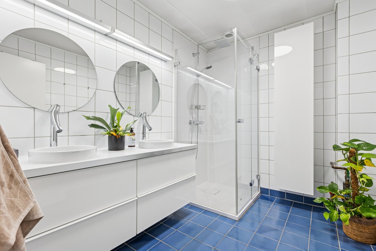 Lyst og funksjonelt bad med fliser, gulvvarme og dusjhjørne med dører. Galleribilde