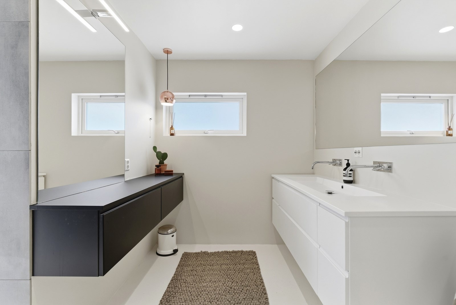 Baderomsinnredningen er også fra Designa, og har to nedfelte servanter med kran integrert i vegg, samt et tilpasset, minimalistisk speil. Galleribilde