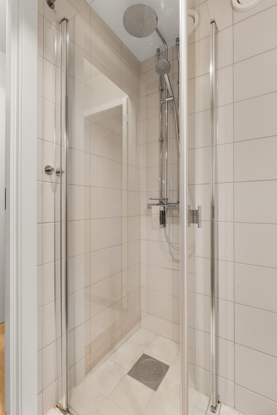 Plassbesparende dusjhjørne med innfellbare glassdører i herdet glass. Galleribilde