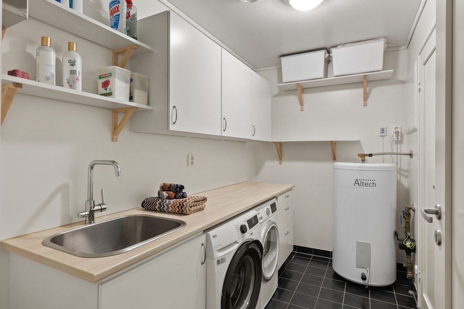 Vaskerom i sokkel på 5,5 kvm. Utstyrt med skap og skyllekum, bereder, stoppekran, vannmåler, rørfordelingsskap og mekanisk avtrekk. Galleribilde