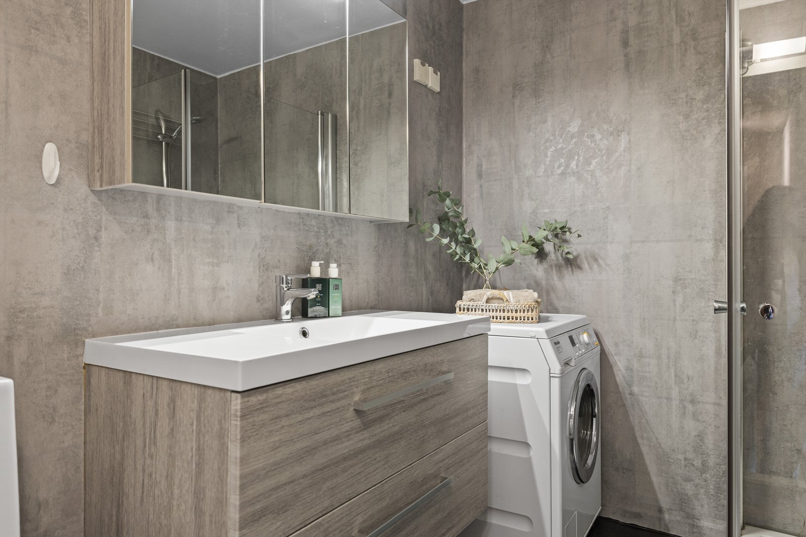 Speilskap, servantskuffer og høyskap langs vegg gir godt med oppbevaringsplass på badet. Galleribilde