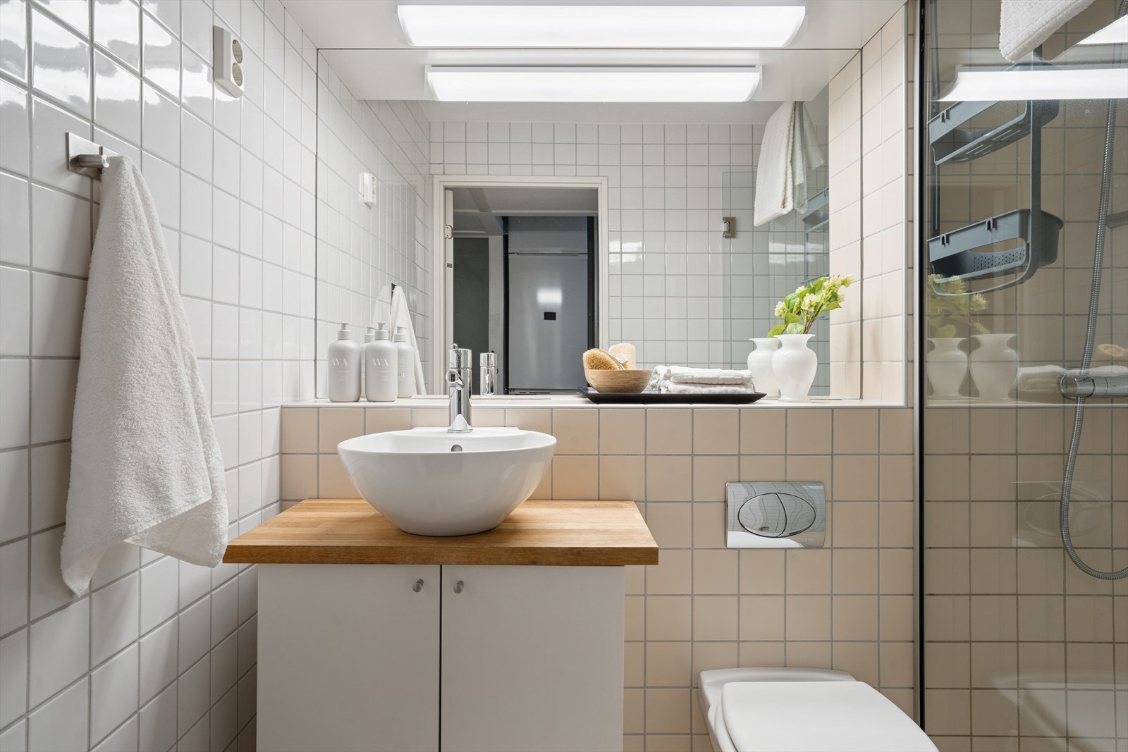 Rommet har en god størrelse og er utstyrt med varmekabler i gulvet for økt komfort. Veggmontert toalett gir et rent uttrykk, og innredningen består av servant med glatte, hvite skapfronter, speil og belysning over Galleribilde