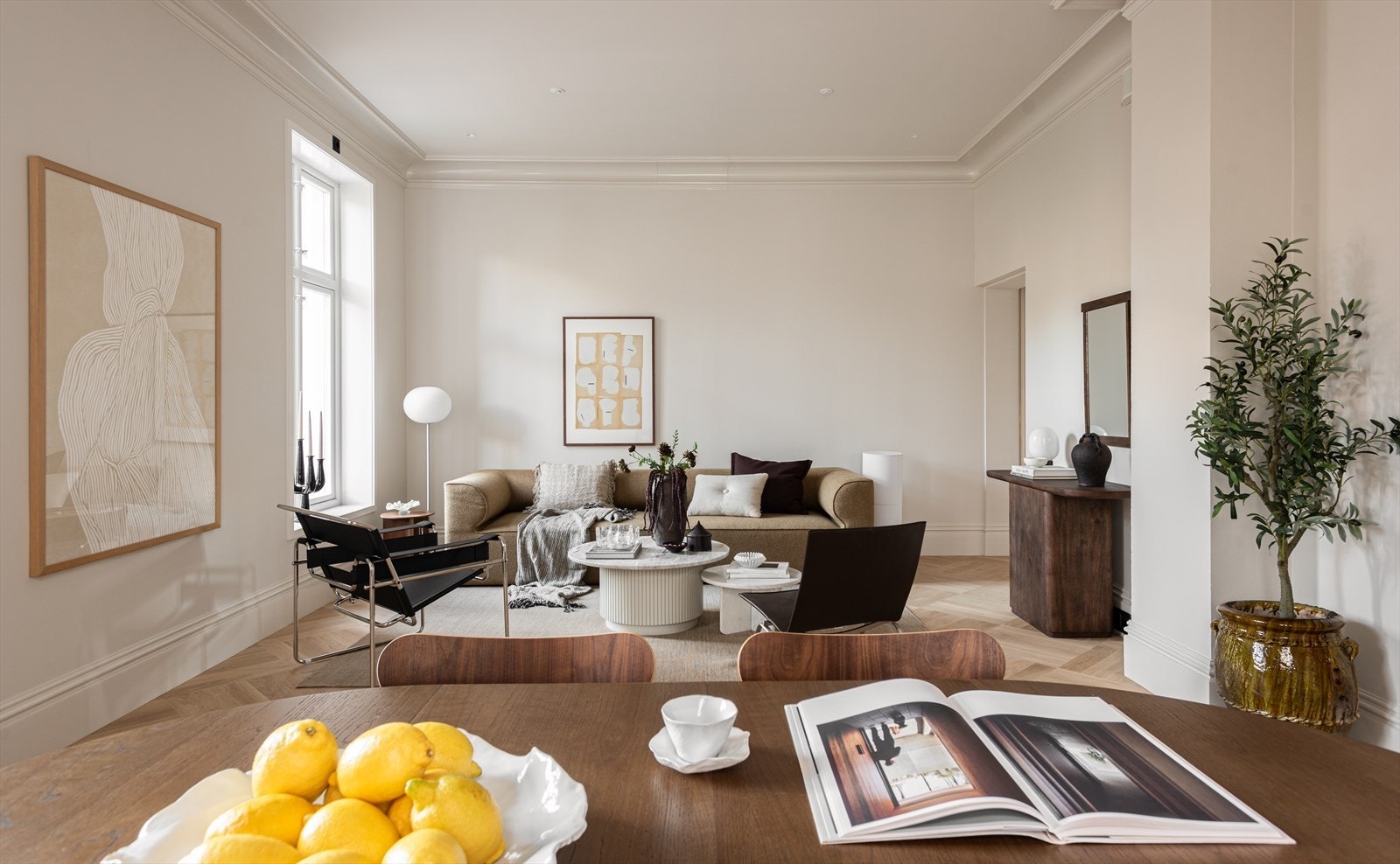 Store vindusflater gir rikelig dagslys, og i kombinasjon med den høye himlingen får stuen en åpen og luftig atmosfære Galleribilde