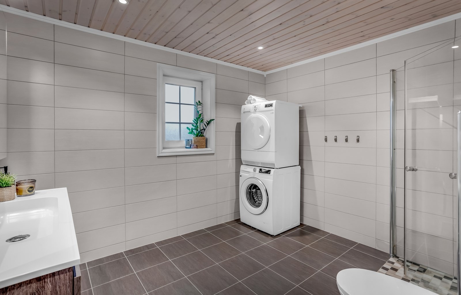 Badet har flislagte overflater, varme i gulvet og opplegg for vaskemaskin og tørketrommel. Galleribilde