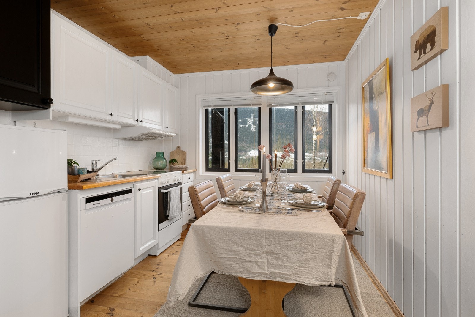 Innredningen er stilren med hvite, profilerte fronter og heltre benkeplate, samt flislagt vegg mellom over- og underskapene for enkel rengjøring. Galleribilde