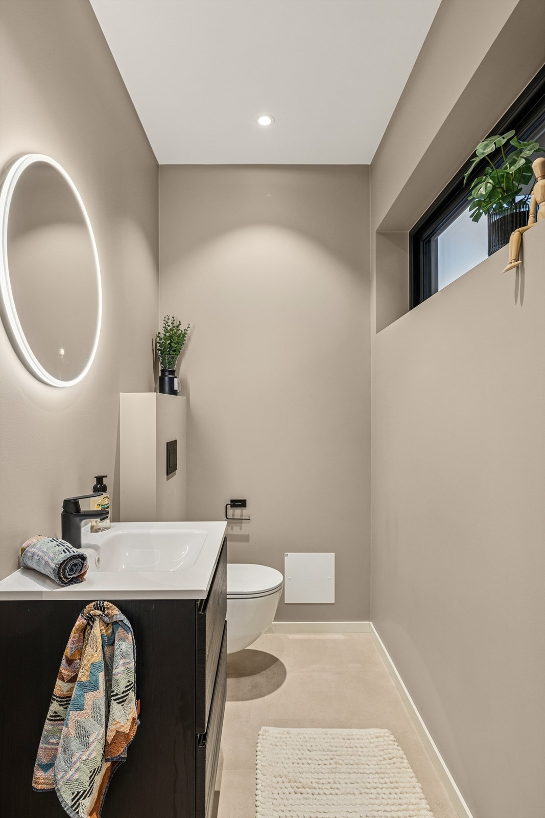 Lyst og pent toalettrom med vegghengt wc og vask nedfelt i skapinnredning. Galleribilde