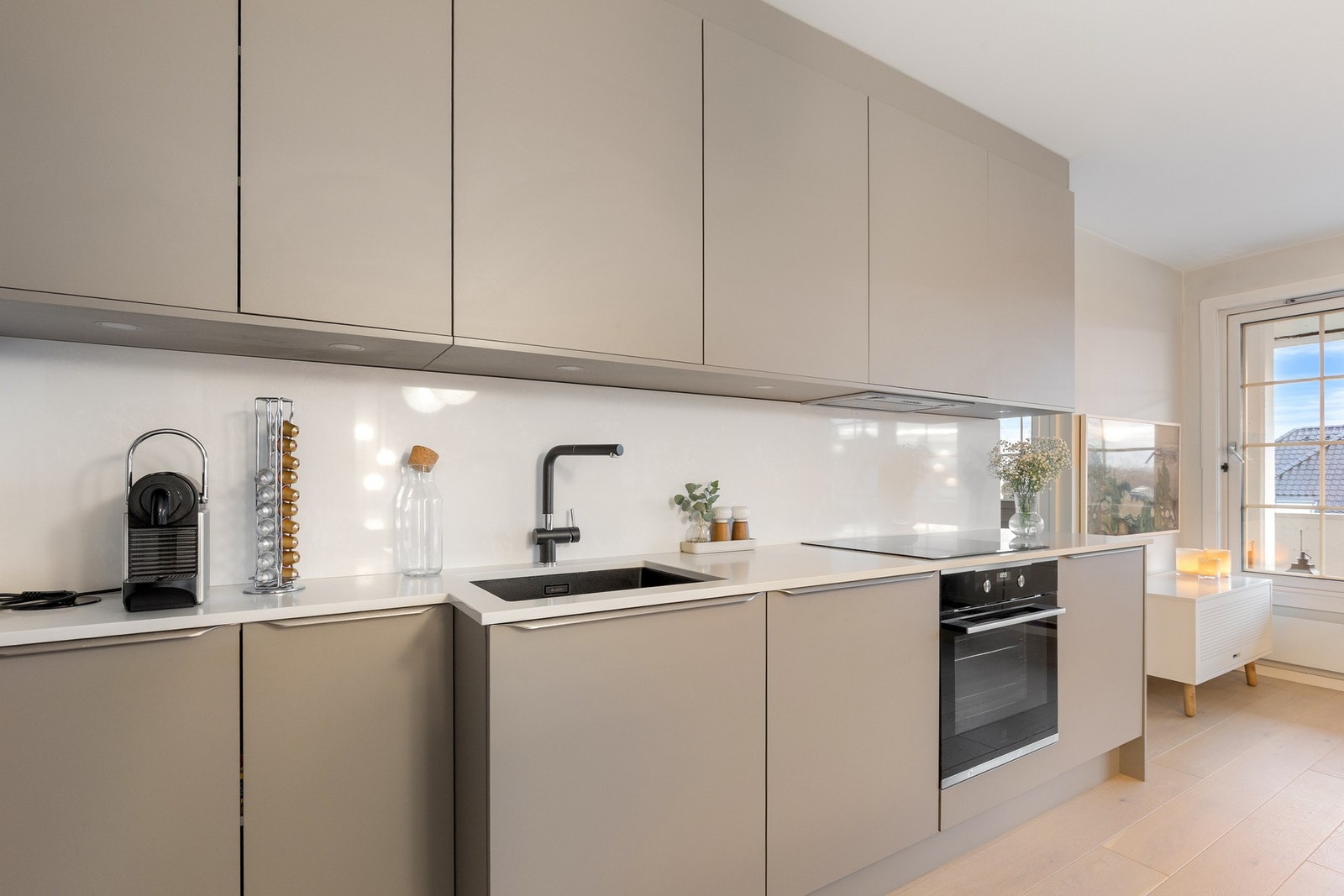 Kjøkkenet har kompositt benkeplate med underlimt sort vask fra Easystone, nedfelt el-uttak samt integrert kjøleskap. Galleribilde