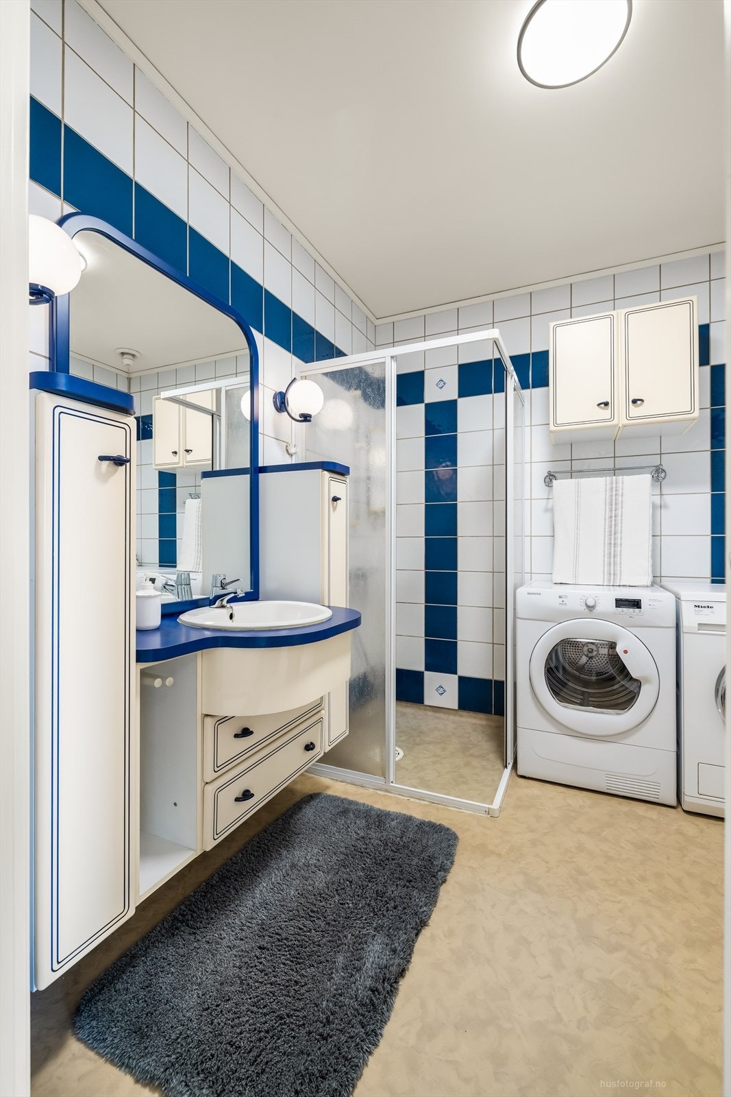 Eldre bad med fliser på vegg og malt tak. Gulvet har vinylbelegg. Galleribilde