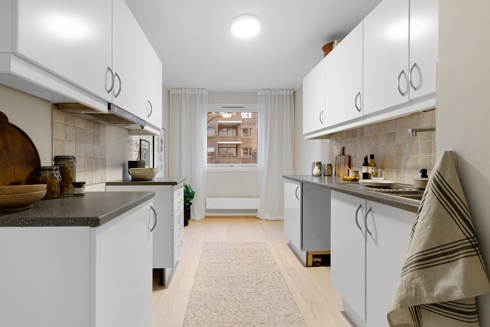 Lyst kjøkken i eget rom, med profilerte fronter og laminert benkeplate. Galleribilde