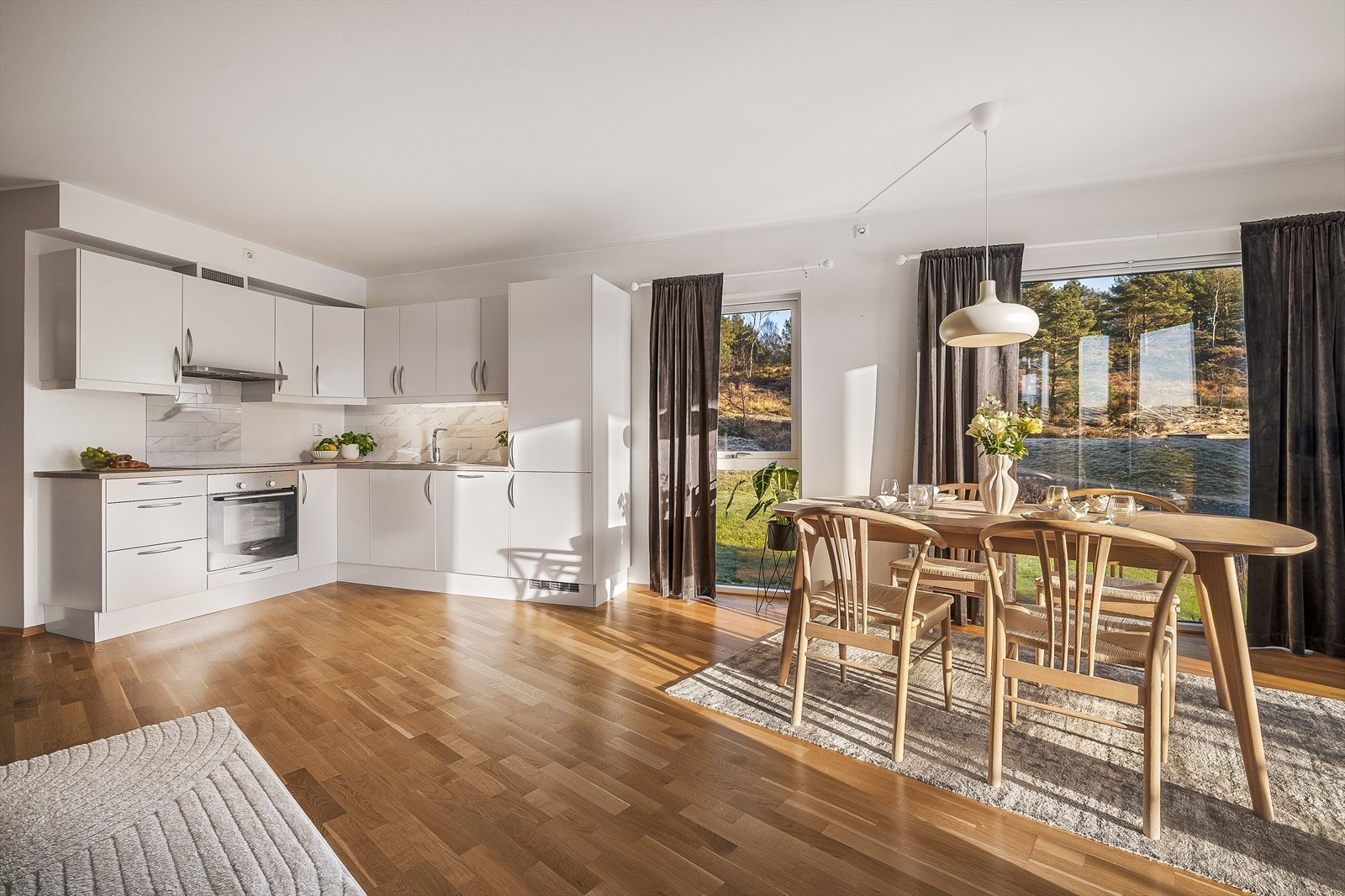 Pent kjøkken med hvite slette fronter og integrerte hvitevarer Galleribilde