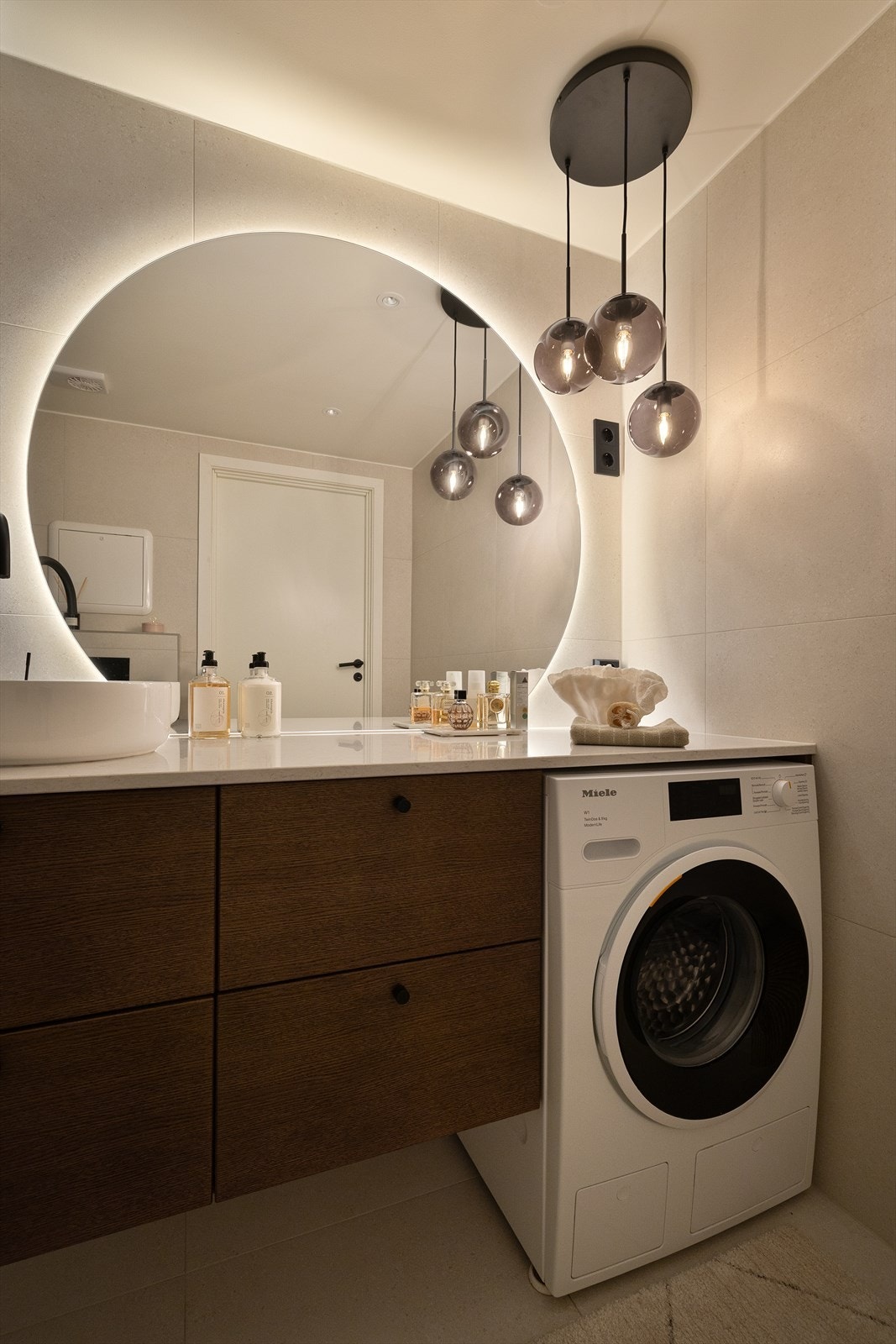 Stilrent bad med helhetlig innredning og kompositt benkeplate - en tydelig rød tråd fra kjøkkenet. Store speilflater og behagelig belysning gir en lun og moderne atmosfære. Galleribilde